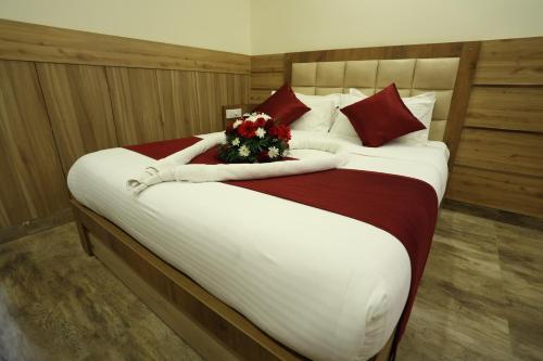 a large bed with a bouquet of flowers on it at Balaji Regency Kanhangad in Kānnangād