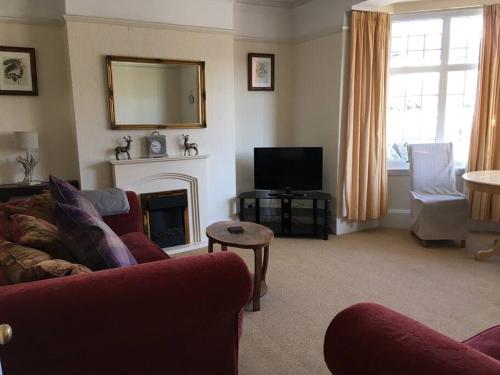 Una sala de estar con un sofá rojo y una chimenea. en Brook Lodge Garden Flat, en Swanage
