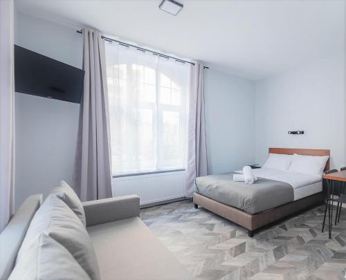 a bedroom with a bed and a couch and a window at Zefiro Seredyńskiego in Gdańsk