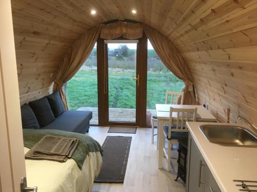 ダンガノンにあるOrchard Luxe Glamping Podのシンクとベッドが備わる小さな家の中にあるベッドルームです。