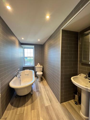 a bathroom with two sinks and a tub and a toilet at Greshornish House Hotel in Edinbane