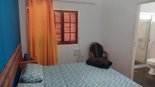 a bedroom with a bed and a toilet and a window at Rose`s place in Mindelo