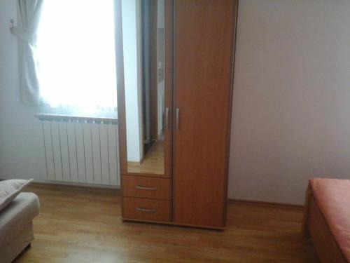 a wooden cabinet with a mirror in a room at Apartments Dale in Smoljanac