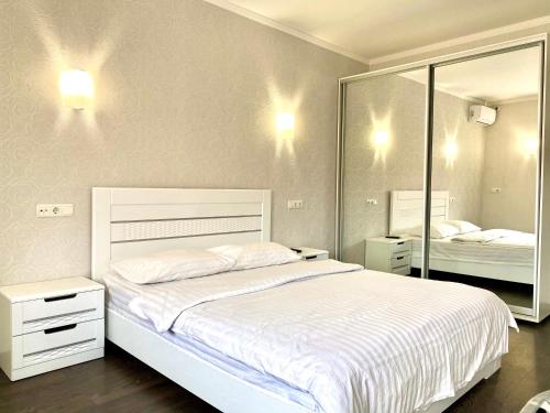ein Schlafzimmer mit einem weißen Bett und einem großen Spiegel in der Unterkunft 2-кімн Просторі апартаменти ,світлий, стриманий дизайн in Poltawa
