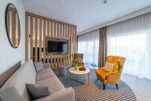 ルチャネ・ニダにあるMazurski Raj - Hotel, Marina & Spaのリビングルーム(ソファ、椅子、テレビ付)