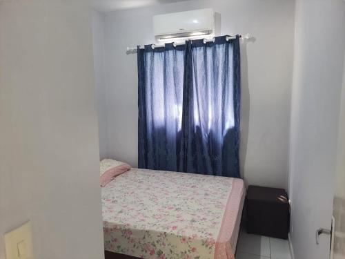 a small bedroom with a bed and a blue curtain at Casa proximo a praia in Paulista