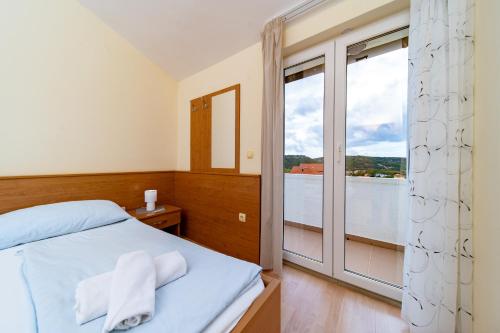 a bedroom with a bed and a large window at Apartments Stare Brajde in Lopar