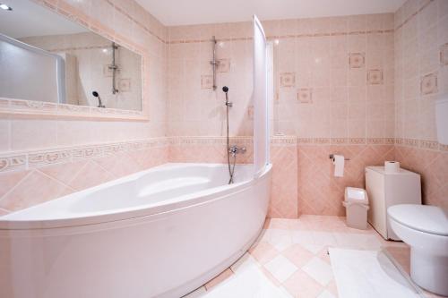 a bathroom with a large tub and a toilet at Apartments Stare Brajde in Lopar