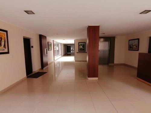 un gran pasillo con suelo de baldosa blanca y un pilar en Departamento Caseros Desings en Salta