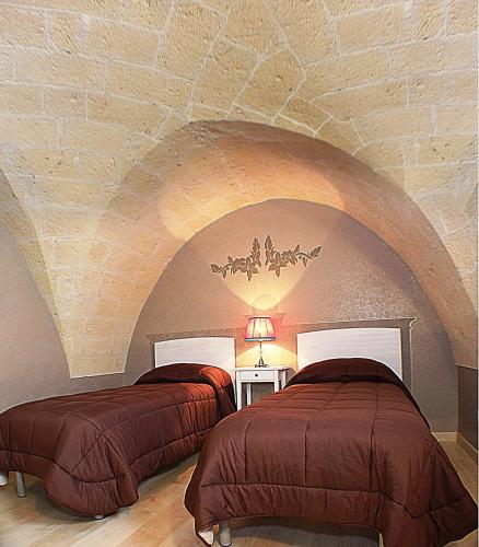 two beds in a room with a stone ceiling at B&B Duca Orsini in Gravina in Puglia
