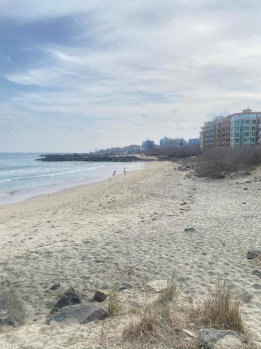 a beach with people walking on the sand and the ocean at Modern Apartment for 4 Guests Sea View & Free Parking in Pomorie