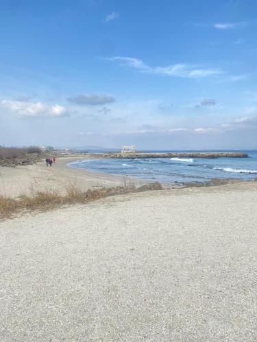 a beach with people walking on the sand and the ocean at Modern Apartment for 4 Guests Sea View & Free Parking in Pomorie