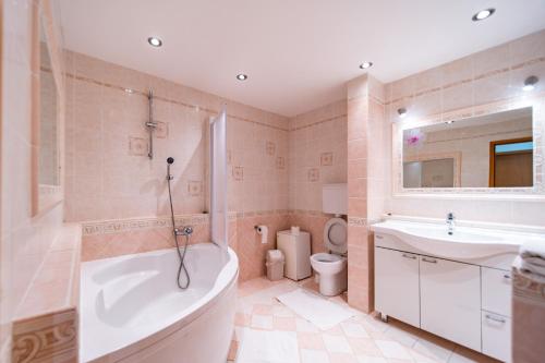 a bathroom with a tub and a sink and a toilet at Apartments Stare Brajde in Lopar