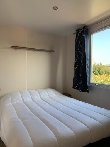 un grand lit blanc dans une chambre avec une fenêtre dans l'établissement Camping Le Montourey, à Fréjus