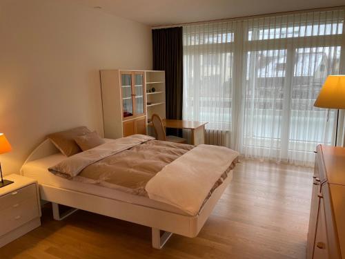 a bedroom with a bed and a desk and a window at Tertianum Parkresidenz Meilen in Meilen