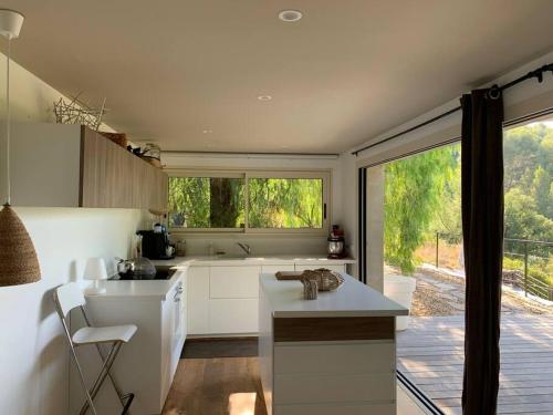 a kitchen with white cabinets and a large window at CABANON in Carqueiranne