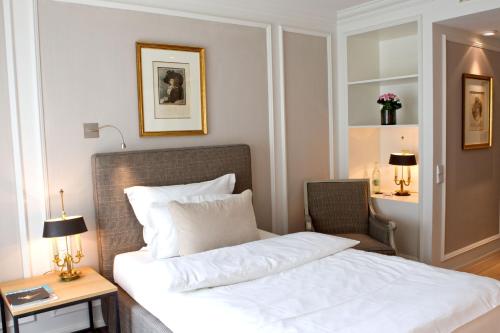 a hotel room with a bed and a chair at Hotel München Palace in Munich