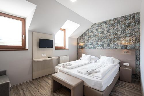 een slaapkamer met een groot wit bed en een televisie bij Gasthaus Panzió in Szilvásvárad