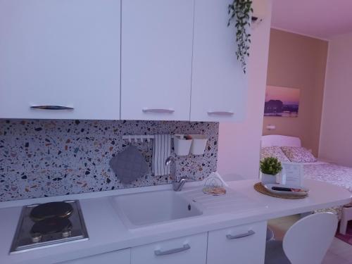 a white kitchen with a sink and a bed at Residence Le Isole in Marsala