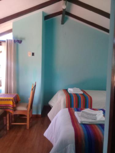 a room with two beds and a chair and a table at Quilla Wasi - ISLA DEL SOL in Comunidad Yumani
