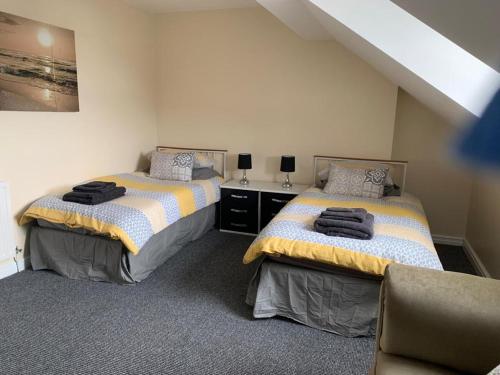 a bedroom with two beds and a chair in it at RUDGRAVE SQUARE WALLASEY in Wallasey