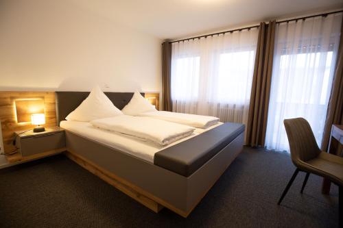 a bedroom with a bed and a chair and a window at Pension Landgasthof Schützen in Tengen