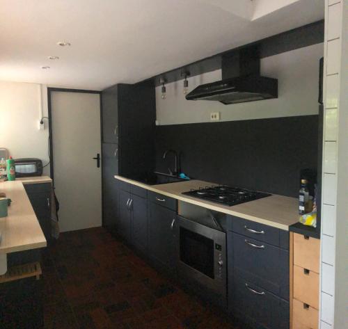 a kitchen with black cabinets and a stove top oven at 8 p bungalow in bossen bij Capfun Stoetenslagh in Rheezerveen