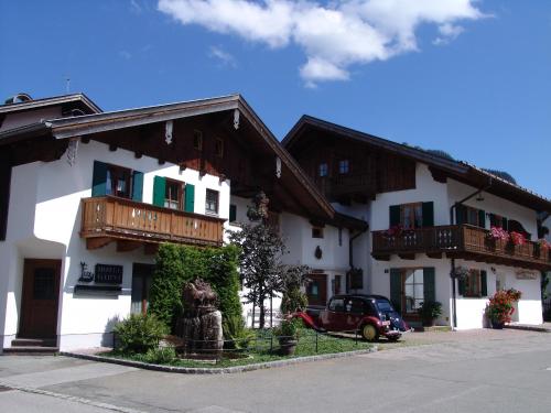 un edificio bianco con balconi in legno e una macchina parcheggiata fuori di Hotel Ferienhaus Fux a Oberammergau