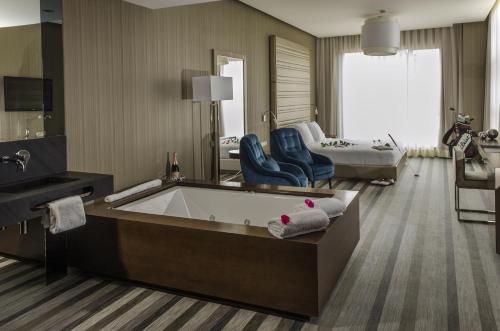 um grande quarto de hotel com uma banheira e uma cama em Retamares Suites & Golf - a sólo 30 mn de Madrid - Vistas a los lagos y Montaña - Ven a descansar !! 