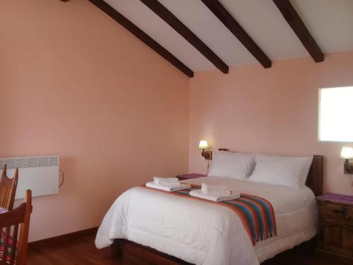 a bedroom with a bed with white sheets and a window at Quilla Wasi - ISLA DEL SOL in Comunidad Yumani