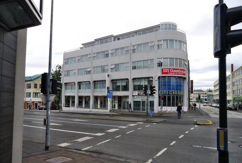 a large white building on a city street with a person crossing the street at 101 Guesthouse Hotel in Reykjavík