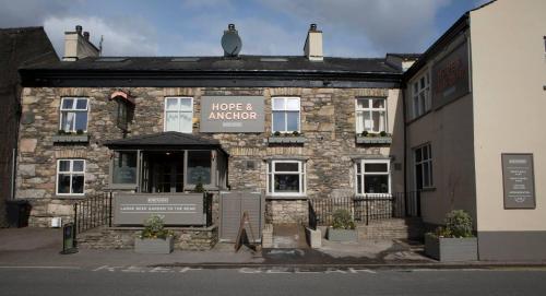 an old stone building with a sign in front of it at Hope and Anchor in Flookburgh