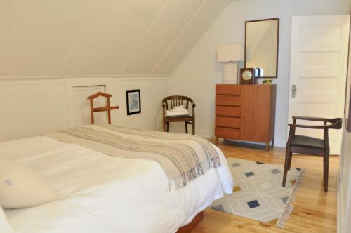 a bedroom with a bed and a dresser and chairs at Napier House in Campbellton