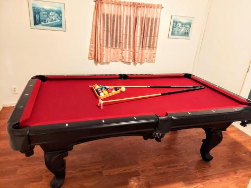 a red pool table with two cuesticks on it at Julian House of Games in Julian