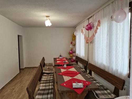 un comedor con una mesa larga con servilletas rojas en Къща за гости Мечта, en Yagodina