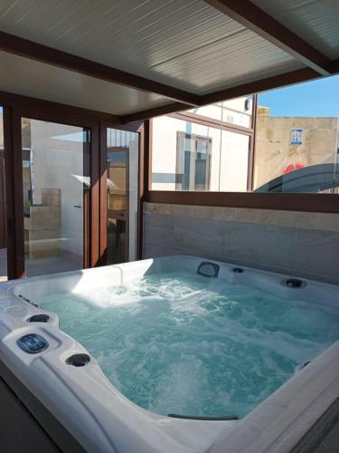 a jacuzzi tub in a room with a window at Ta Wigi Farmhouse in Żebbuġ