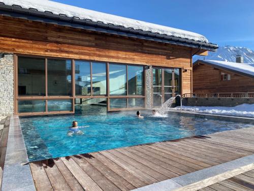 - 2 personnes dans une piscine à côté d'une maison dans l'établissement Chalet Emeraude - 10 personnes - Plagne Soleil, à Plagne Villages