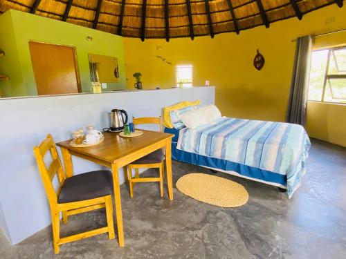 a bedroom with a table and a bed and a table and chair at Izulu Eco Lodge in Sodwana Bay