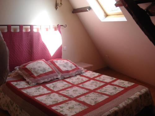 une chambre avec un lit avec une couverture rouge et une fenêtre dans l'établissement le manège de Royaumont, à Saint-Arnoult