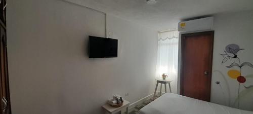 a bedroom with a bed and a television on the wall at Hotel Habibi in Barranquilla