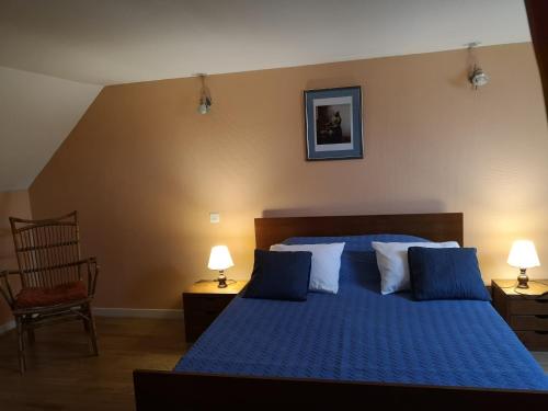 a bedroom with a blue bed with two lamps and a chair at Maisonnette La Bienvenue in Trainel