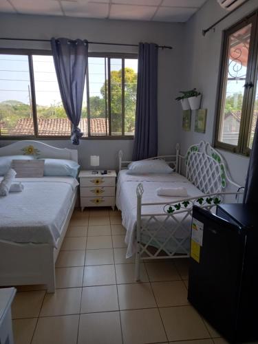two beds in a room with two windows at Hostel Kimmell / Hostal Familiar La Casita De Los Kimmell in Las Tablas