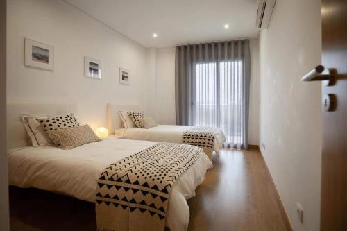 a hotel room with two beds and a window at Residência Bela Vida in São Martinho do Porto