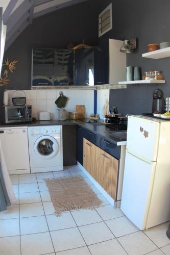 a kitchen with a washing machine and a washer at Le Blue CoCo - 1 minute de la plage in Sainte-Anne