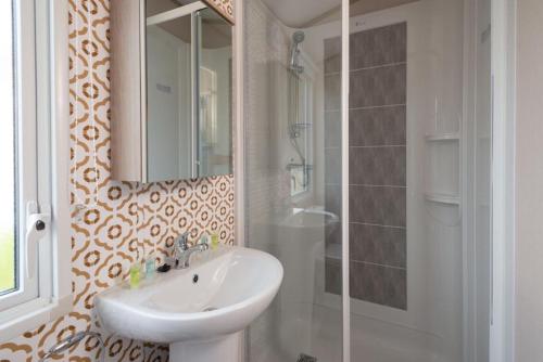 a bathroom with a sink and a mirror and a shower at Luxury Holiday Home Sleeps 6 Pet Friendly in St Austell