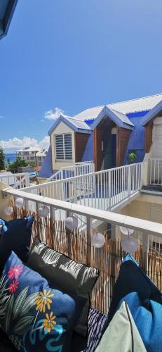 a balcony with chairs and pillows on a house at Le Blue CoCo - 1 minute de la plage in Sainte-Anne