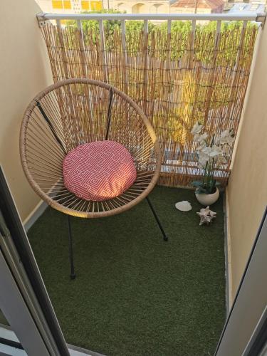 a rattan chair with a pink pillow sitting on a balcony at Le Blue CoCo - 1 minute de la plage in Sainte-Anne