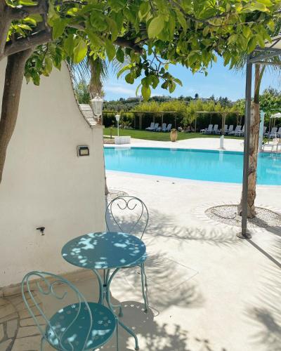 a table and chairs next to a swimming pool at All`Ombra del Carrubo in Polignano a Mare