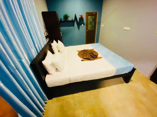 a small bedroom with a white bed with blue walls at Nilaveli Hybrid Holiday Hotel in Nilaveli