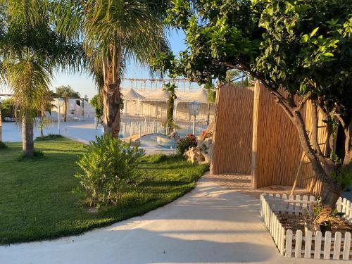 a sidewalk leading to a house with a fence and trees at All`Ombra del Carrubo in Polignano a Mare